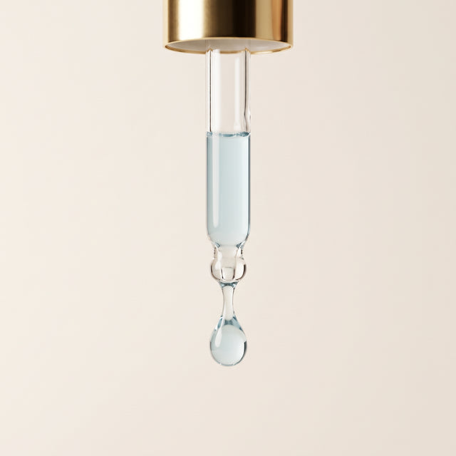 Pipeta dourada com uma gota de sérum Stella translúcido de tom azul suave.