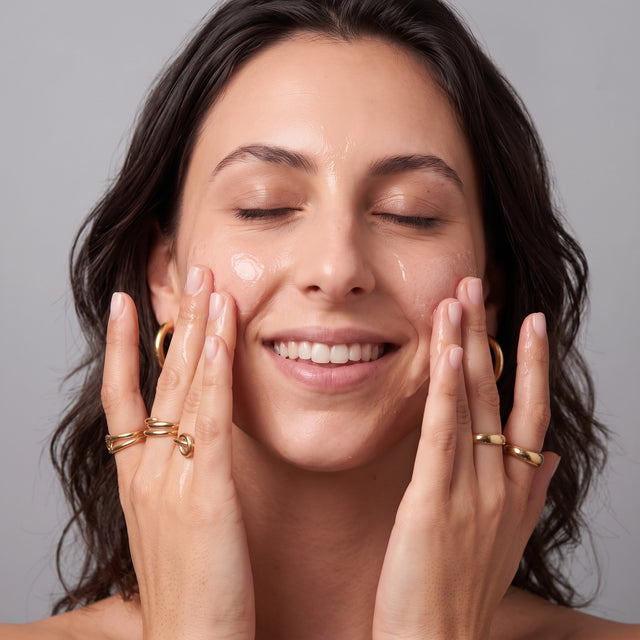Mulher a massajar suavemente o sérum nas faces com as pontas dos dedos.