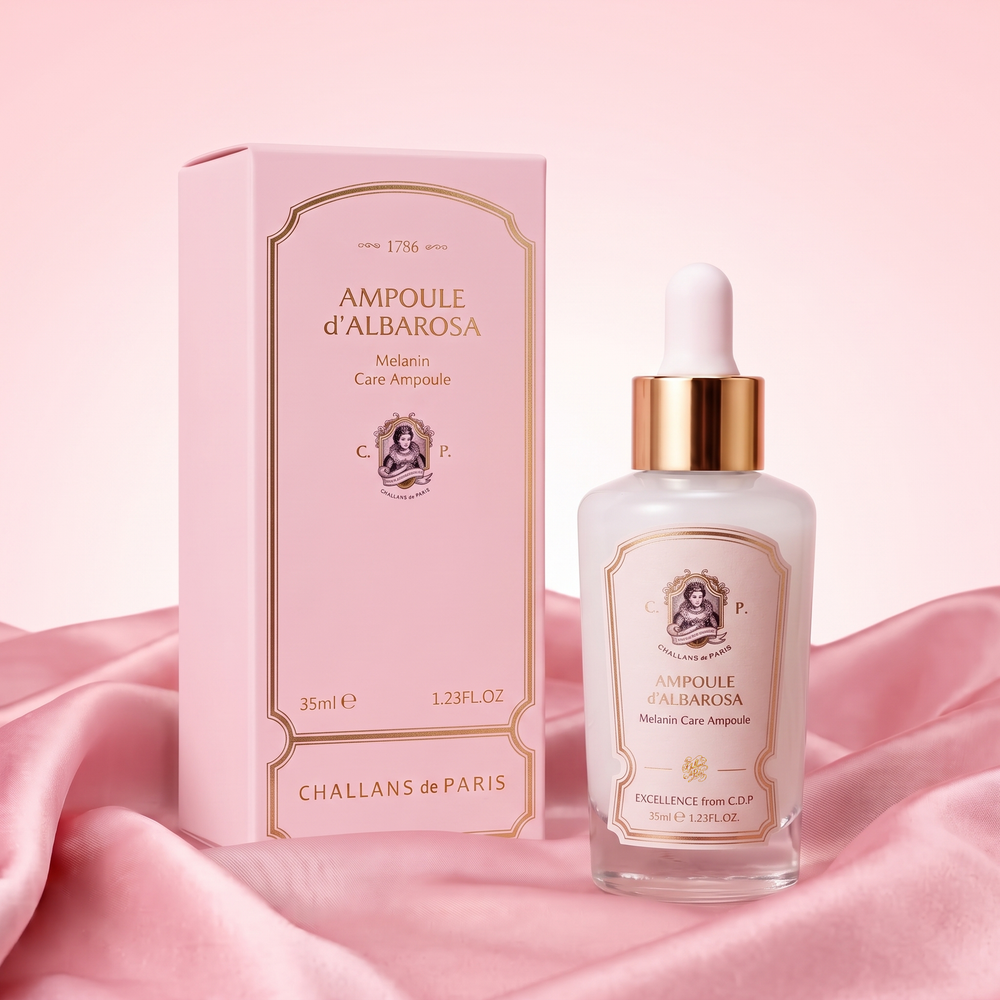 Challans de Paris Ampoule d'Albarosa next to its product box, featuring a pink box and a clear glass dropper bottle with a gold collar, set against a pink satin background.
