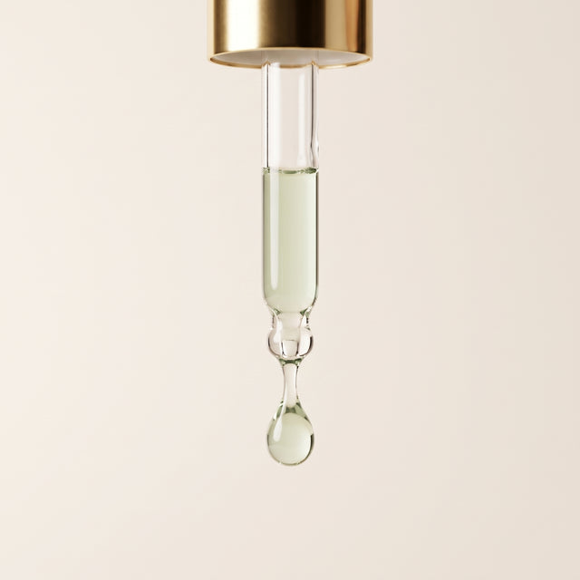 Pipeta dourada com uma gota de sérum Aurora translúcido de tom verde suave.